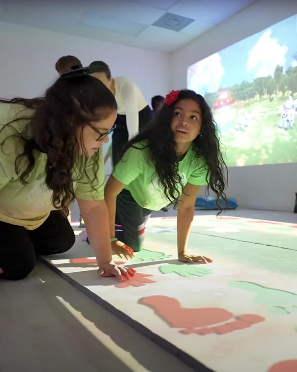 Two girls interacting with projected hand and foot prints on interactive floor